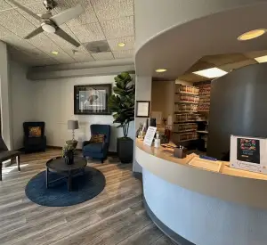 Reception desk and lounge area — curved counter, plants, and comfortable chairs