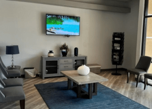 Modern dental waiting area with TV, coffee table, and cozy seating