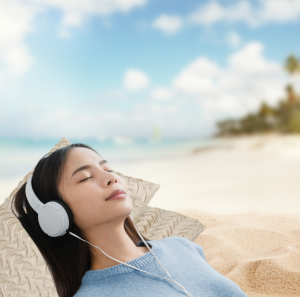 Woman relaxing on beach with headphones — calm, stress-free vibe